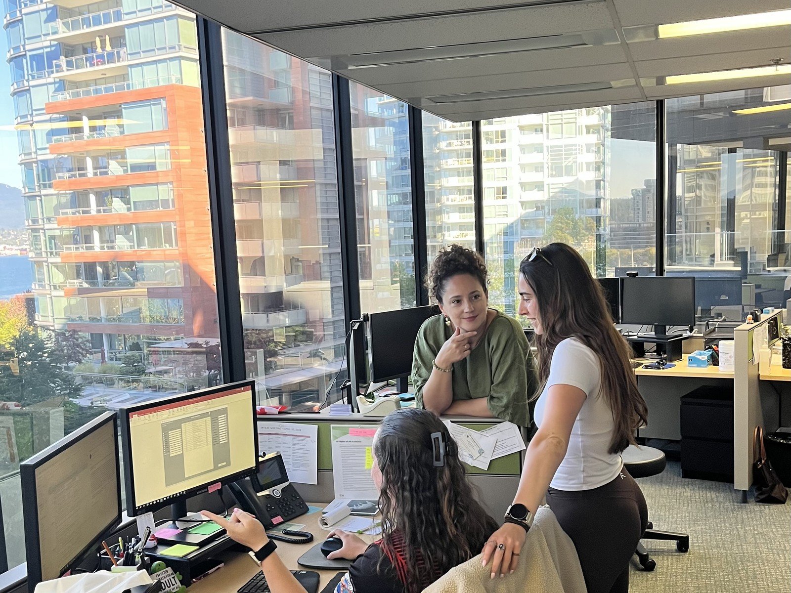 IMA Solutions team members reviewing work together at a desk in the Vancouver office